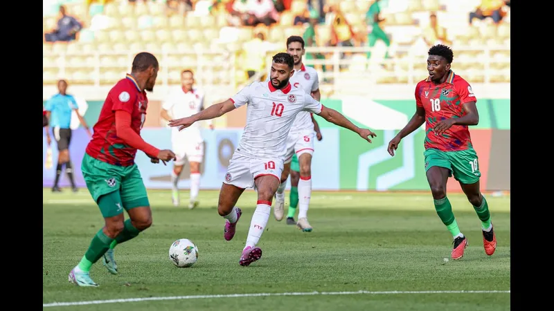 Cầu thủ Tunisia với áo đỏ đang nỗ lực vượt qua cầu thủ Namibia trong trận đấu bóng đá.